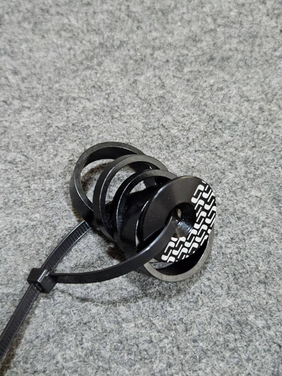 Pulsera de silicona negra con diseño geométrico en una superficie gris.