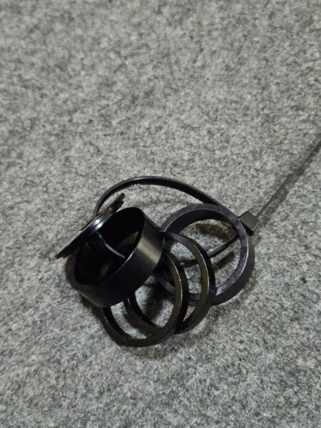 Anillos de metal negros apilados sobre una superficie gris.