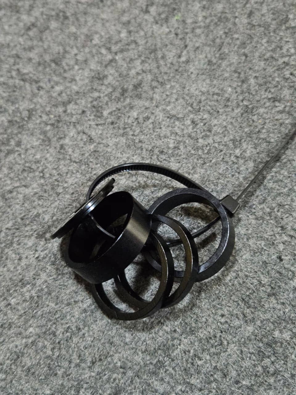 Anillos de metal negros apilados sobre una superficie gris.