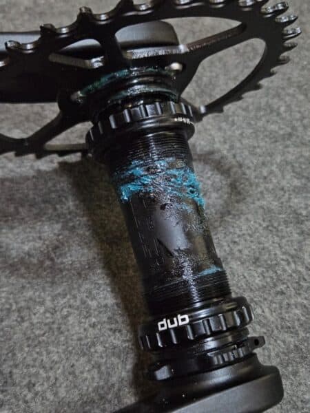 Eje de pedal de bicicleta con desgaste y pintura azul desgastada.