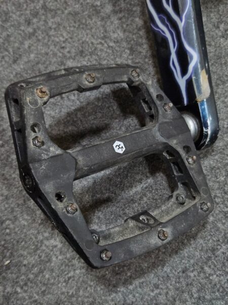Pedal de bicicleta de montaña con estructura resistente y tornillos.