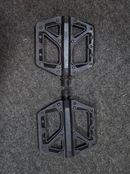Pedales de bicicleta de plataforma negras con tornillos en superficie antideslizante.