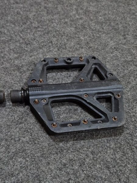 Pedal de bicicleta negro en superficie de goma gris.