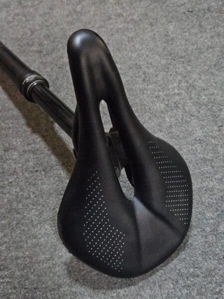 Sillin de bicicleta negro con diseño ergonómico y perforaciones para ventilación.