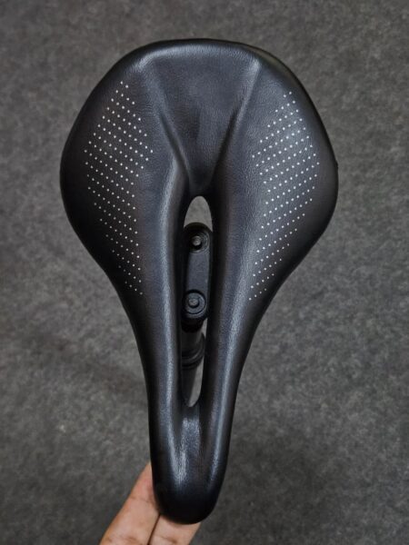 Sillín de bicicleta negro con diseño perforado para mayor comodidad.