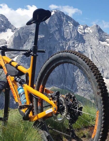 Bicicleta de montaña en paisaje montañoso con picos nevados y cielo azul.